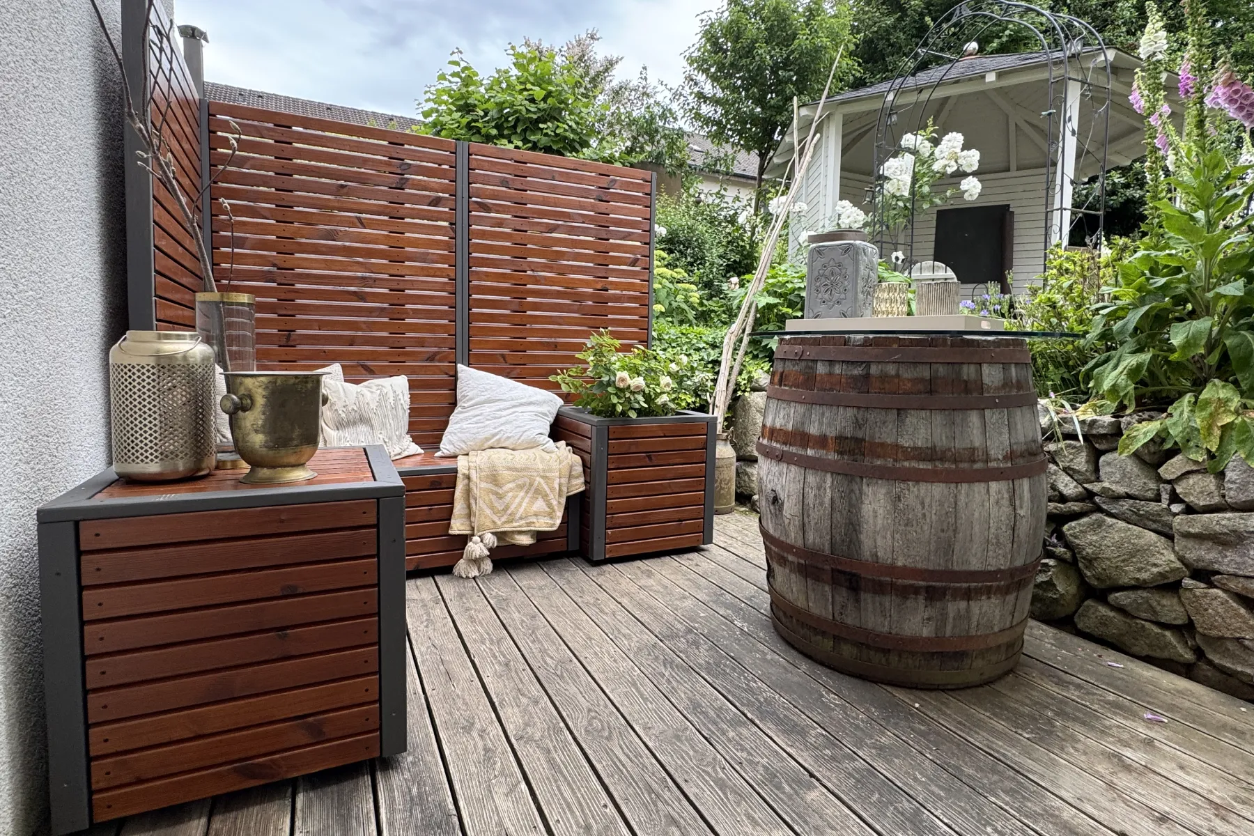 Lounge-System mit Sichtschutz, Sitzbank, Pflanzkübel und Tisch auf einer Terrasse